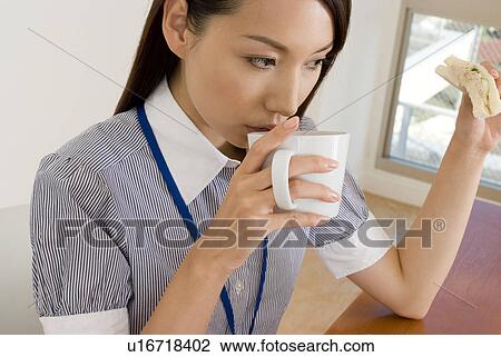 Young woman eating sandwiches at desk View Large Photo Image Stock Image - Young woman eating sandwiches at desk. Fotosearch