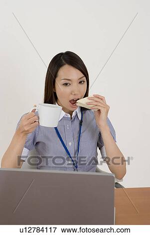Young woman eating sandwiches at desk View Large Photo Image Stock Photo - Young woman eating sandwiches at desk. Fotosearch