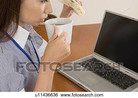 Young woman eating sandwiches at desk View Large Photo Image Stock Photograph - Young woman eating sandwiches at desk. Fotosearch