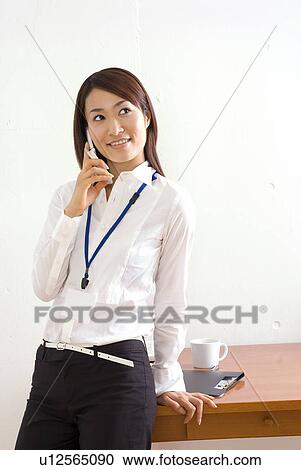 Stock Image - Young woman talking over mobile phone. Fotosearch