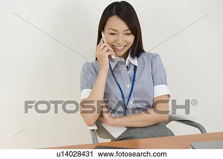 Stock Image - Young woman talking over mobile phone. Fotosearch