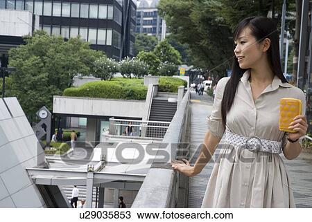 Stock Image - Young woman walking with wallet. Fotosearch