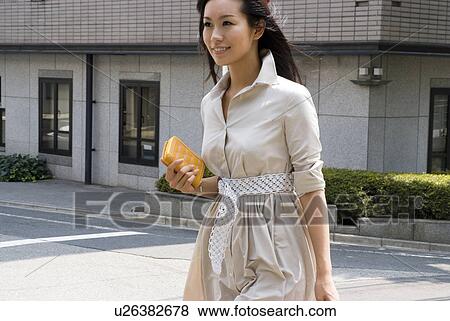 Stock Photo - Young woman walking with wallet. Fotosearch