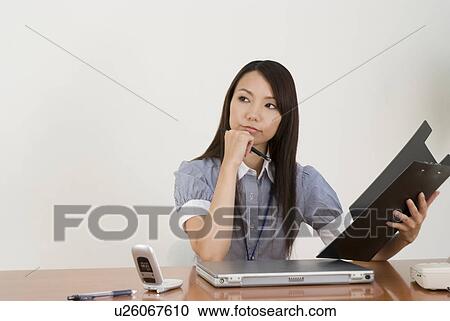 Stock Image - Young woman working in office. Fotosearch