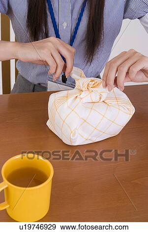 Stock Photo - Young woman wrapping lunch box. Fotosearch