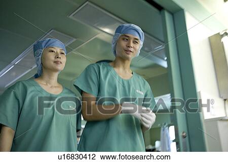 Stock Image - Doctor and nurse walking out of surgery. Fotosearch