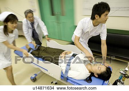 Picture - Doctor and nurses transporting patient on stretcher. Fotosearch