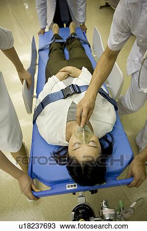 Stock Image - Doctor and nurses transporting patient on stretcher. Fotosearch