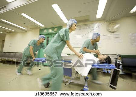 Stock Photo - Doctor and nurses transporting patient on stretcher. Fotosearch