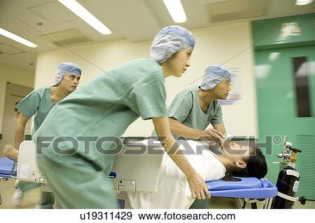 Stock Photo - Doctor and nurses transporting patient on stretcher. Fotosearch