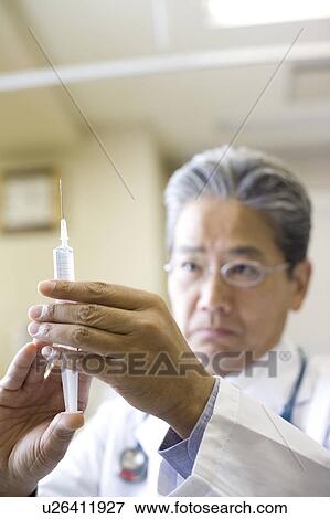 Stock Photo - Doctor holding syringe. Fotosearch