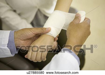 Doctor wrapping bandage around patient's wrist View Large Photo Image Stock Image - Doctor wrapping bandage around patient's wrist. Fotosearch