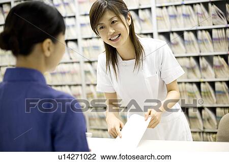 Stock Image - Nurse talking with patient at reception. Fotosearch