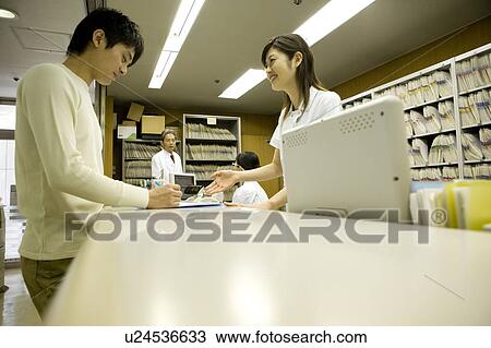 Stock Image - Nurse talking with patient at reception. Fotosearch