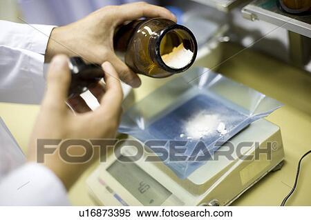 Stock Photography - Pharmacists pouring medicine from bottle. Fotosearch