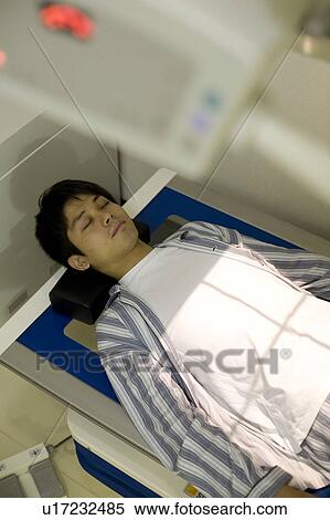 Young man lying on x-ray table View Large Photo Image Stock Photography - Young man lying on x-ray table. Fotosearch
