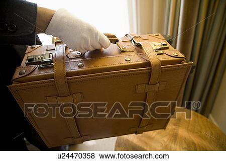 Stock Photo - Bellboy carrying suitcase. Fotosearch
