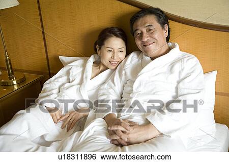 Mature couple relaxing in bed View Large Photo Image Stock Photograph - Mature couple relaxing in bed. Fotosearch