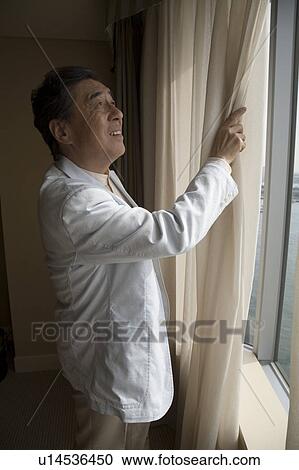 Mature man opening curtain in hotel room View Large Photo Image Stock Image - Mature man opening curtain in hotel room. Fotosearch