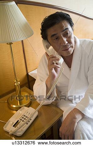 Mature man using telephone in hotel room View Large Photo Image Stock Photograph - Mature man using telephone in hotel room. Fotosearch