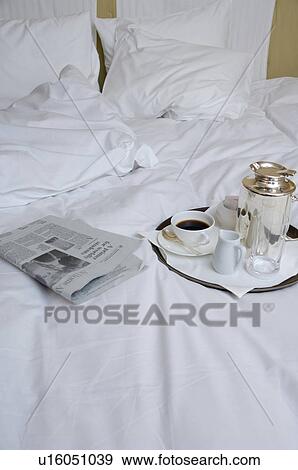 Stock Photo - Newspaper and cup of coffee on bed. Fotosearch