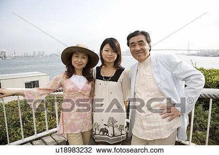 Stock Image - Parents and daughter standing. Fotosearch
