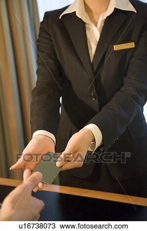 Stock Image - Receptionist giving cardkey to hotel guest. Fotosearch