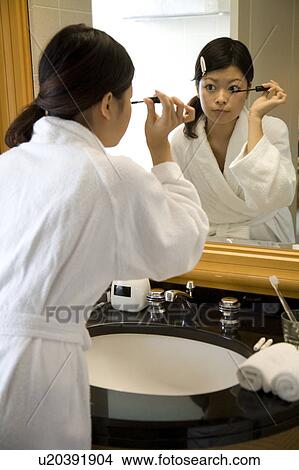 Picture - Young woman applying mascara. Fotosearch