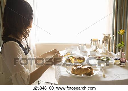 Young woman eating breakfast in hotel room View Large Photo Image Stock Image - Young woman eating breakfast in hotel room. Fotosearch