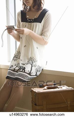 Stock Photograph - Young woman looking at digital camera. Fotosearch