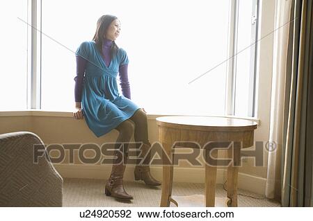 Stock Image - Young woman sitting in hotel room. Fotosearch
