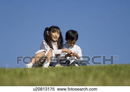 Stock Photography - Boy and girl sitting in field. Fotosearch