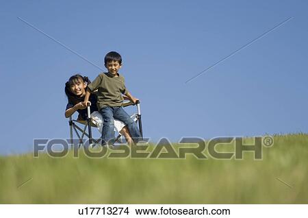 Boy and girl trying to sit in one chair View Large Photo Image Picture - Boy and girl trying to sit in one chair. Fotosearch
