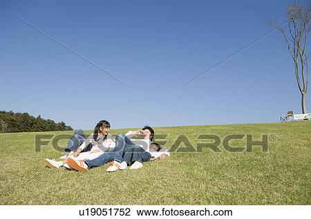 Stock Image - Family lying in field. Fotosearch