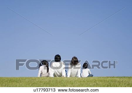 Stock Image - Family sitting in field. Fotosearch