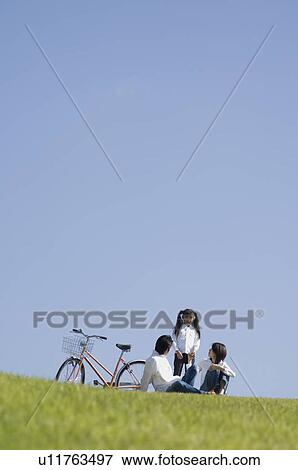 Stock Photo - Family sitting in field. Fotosearch