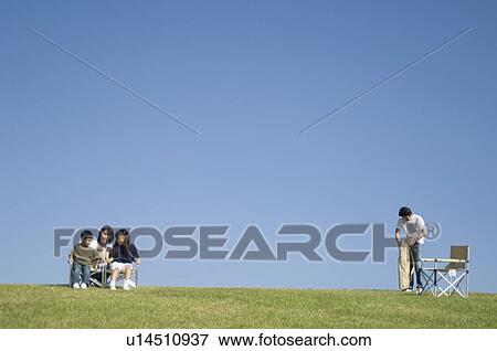 Stock Photo - Family sitting in field. Fotosearch