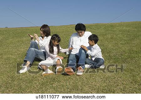 Stock Photo - Family sitting in field. Fotosearch