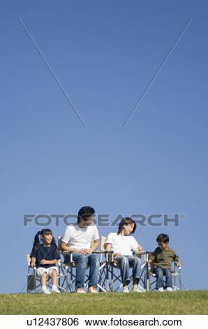 Stock Photograph - Family sitting in field. Fotosearch
