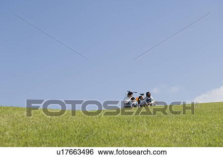 Stock Photograph - Family sitting in field. Fotosearch