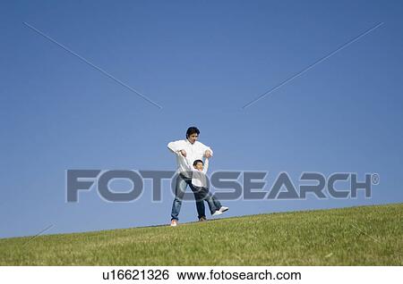 Father and son playing in field View Large Photo Image Stock Photograph - Father and son playing in field. Fotosearch
