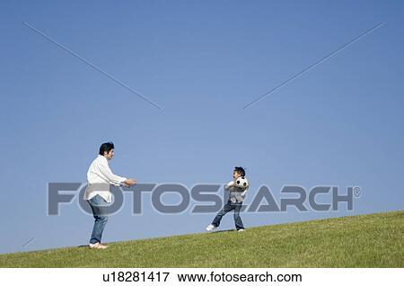 Stock Photo - Father and son playing with soccer ball. Fotosearch