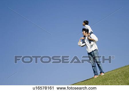 Stock Image - Father giving son piggyback. Fotosearch