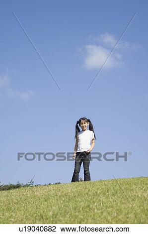 Stock Image - Girl standing in field. Fotosearch