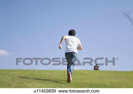 Stock Photo - Mid adult man running in field. Fotosearch