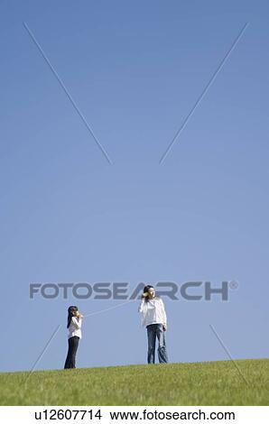 Picture - Mother and daughter using paper cup phone. Fotosearch