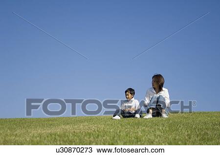 Stock Image - Mother and son sitting in field. Fotosearch