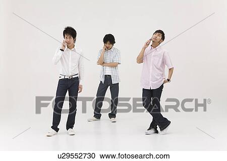 Stock Image - Three young men talking over mobile phones. Fotosearch