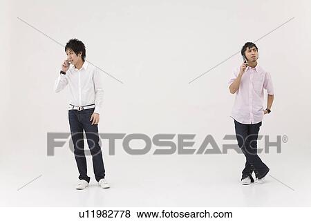 Two young men talking over mobile phones View Large Photo Image Stock Photo - Two young men talking over mobile phones. Fotosearch
