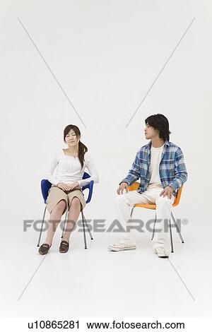 Stock Image - Two young people sitting in chairs. Fotosearch